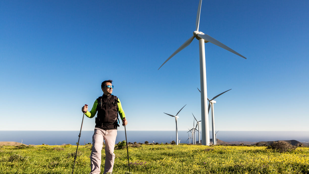 traveling-man-with-trekking-poles-in-field-with-wi-2023-11-27-05-13-12-utc