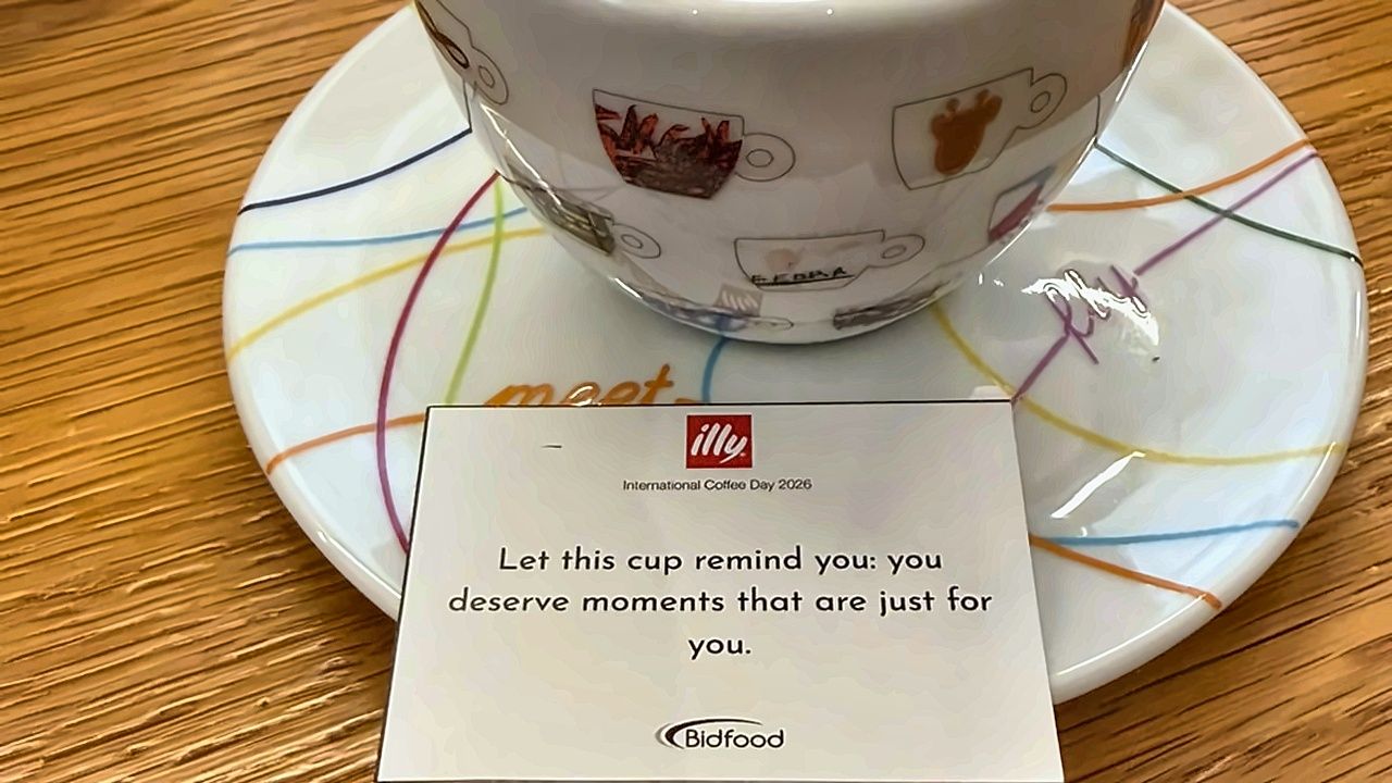 An illy cup and saucer with a Bidfood International Coffee Day 2026 card