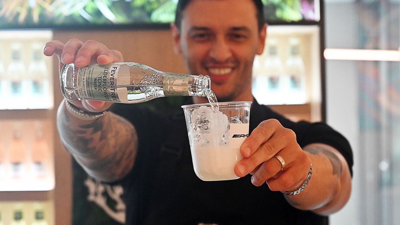 Smiling bartender pouring a mocktail for guests