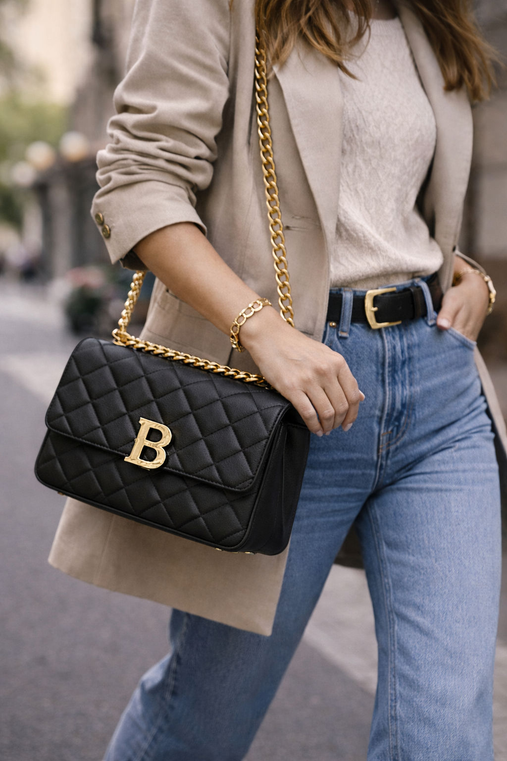 Fashion model walking city street carrying a statement bag.