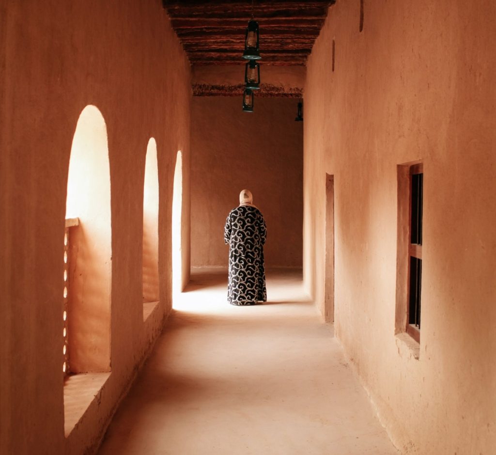 Woman in abaya walking in a traditional hallway