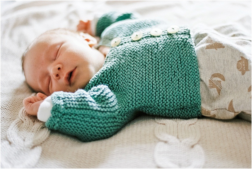 Newborn baby sleeping in knitted, handmade clothes, Hertfordshire.