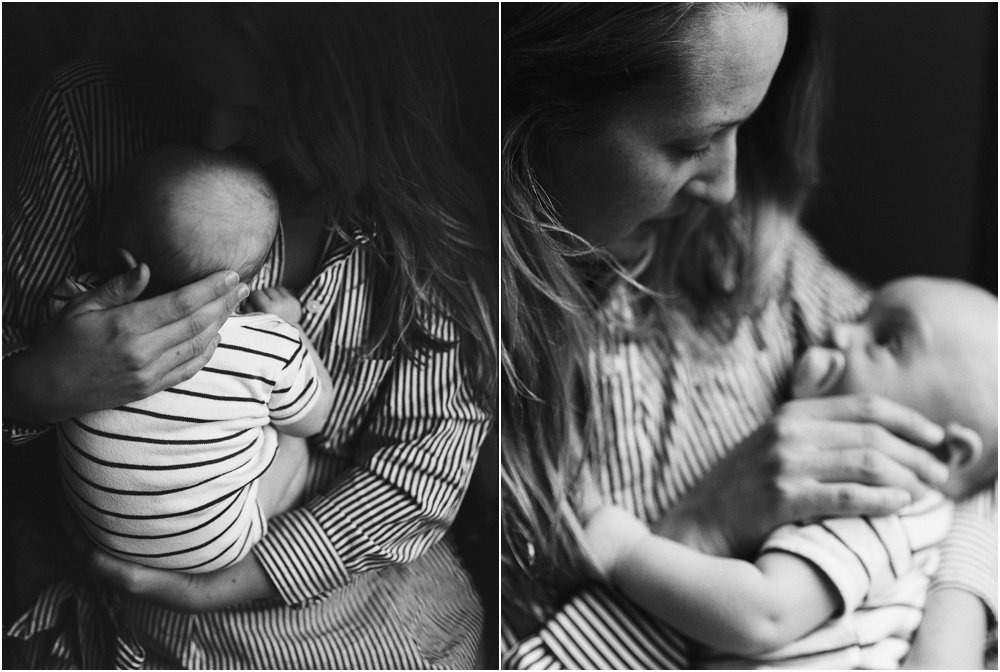 black and white image of mother holding baby gently, looking up.