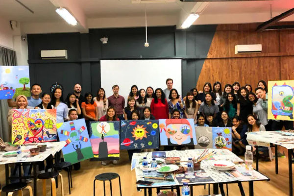 A full room of painters at easels during a session
