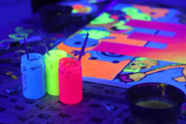 Bottles of neon acrylic paint glowing under UV light
