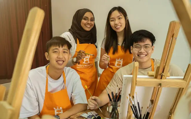 A group of painters in aprons gathered around easels in the studio
