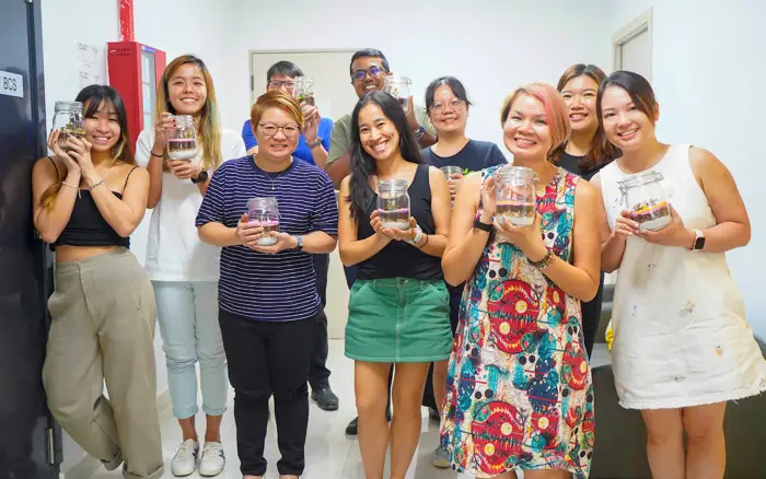 A group of colleagues hold up the terrariums they each made