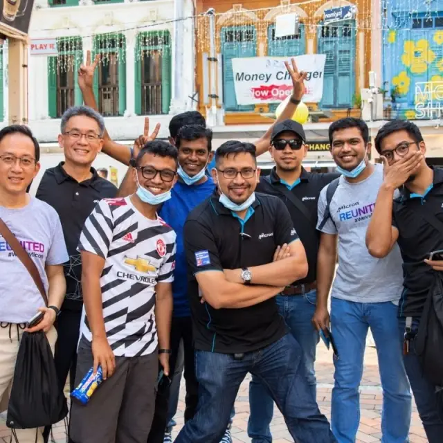 A team of eight pose in front of a row of shophouses