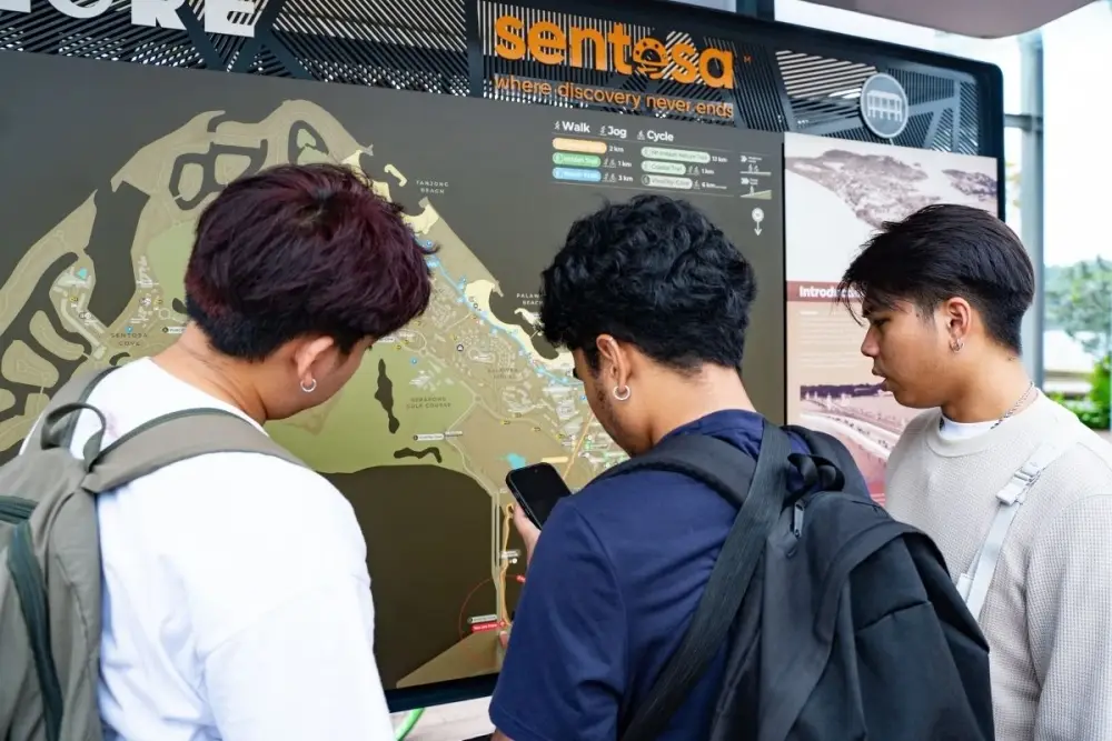 Three teammates study a map board at Sentosa
