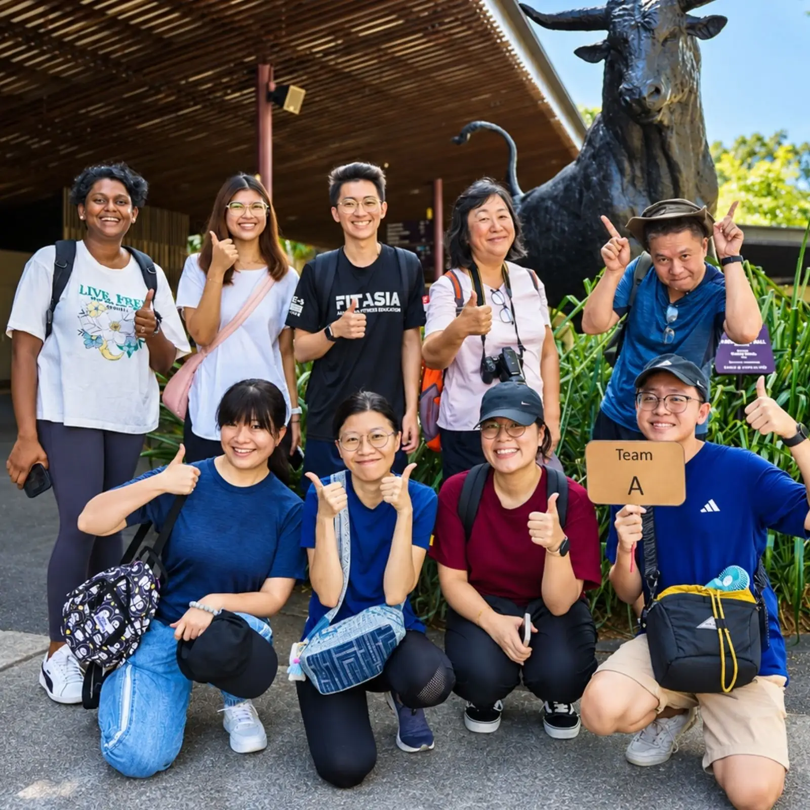 A team of ten pose outdoors with their Team A sign
