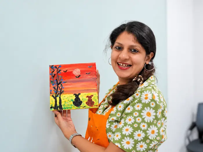 A participant holds up the small canvas she painted