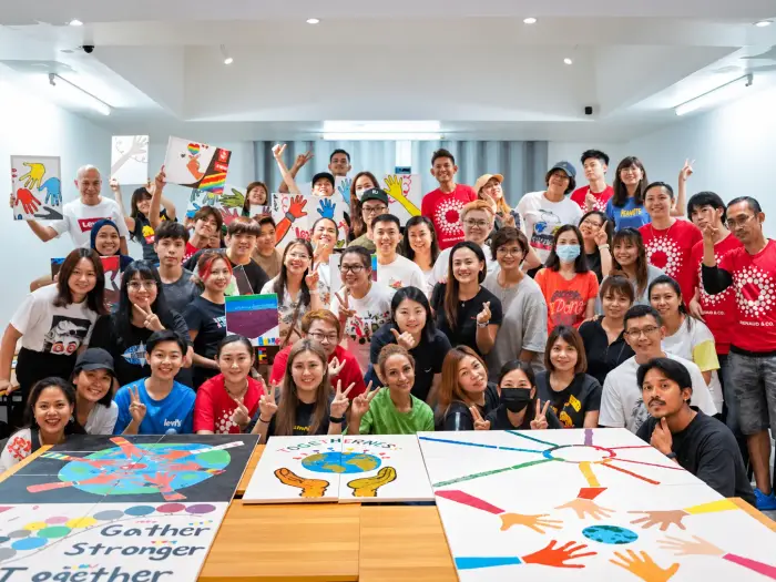 A large company group cheer behind the big canvases they painted together