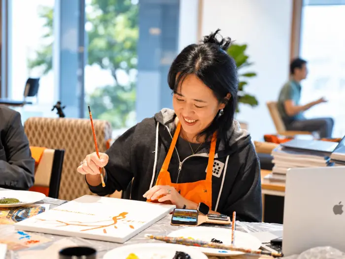 A participant smiles as she paints her canvas