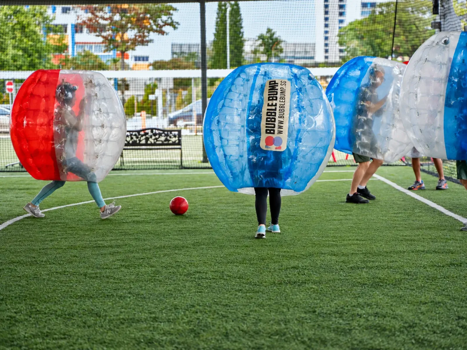 Players in bubble suits on an outdoor pitch with the ball in play