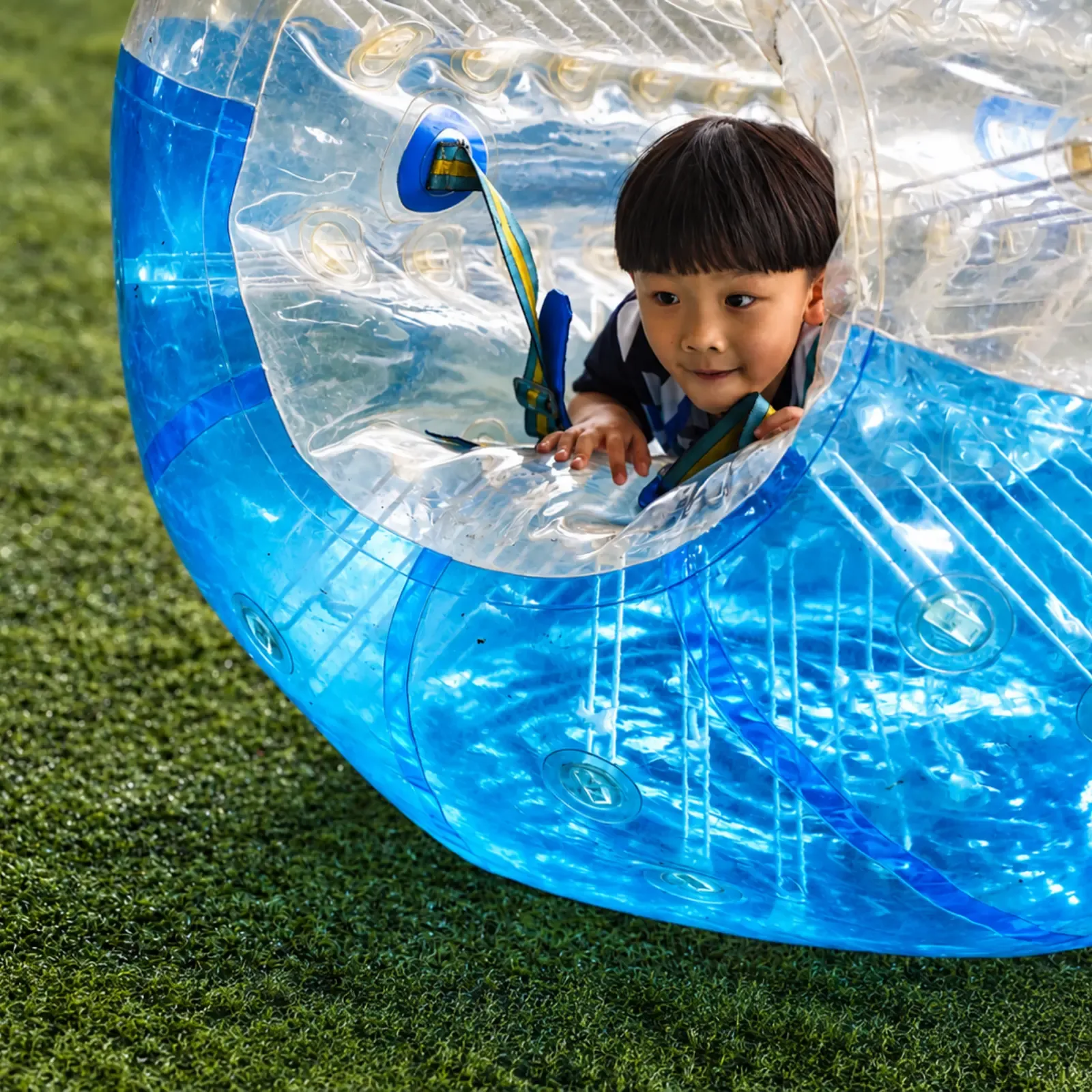 A child grins from inside a blue bubble suit