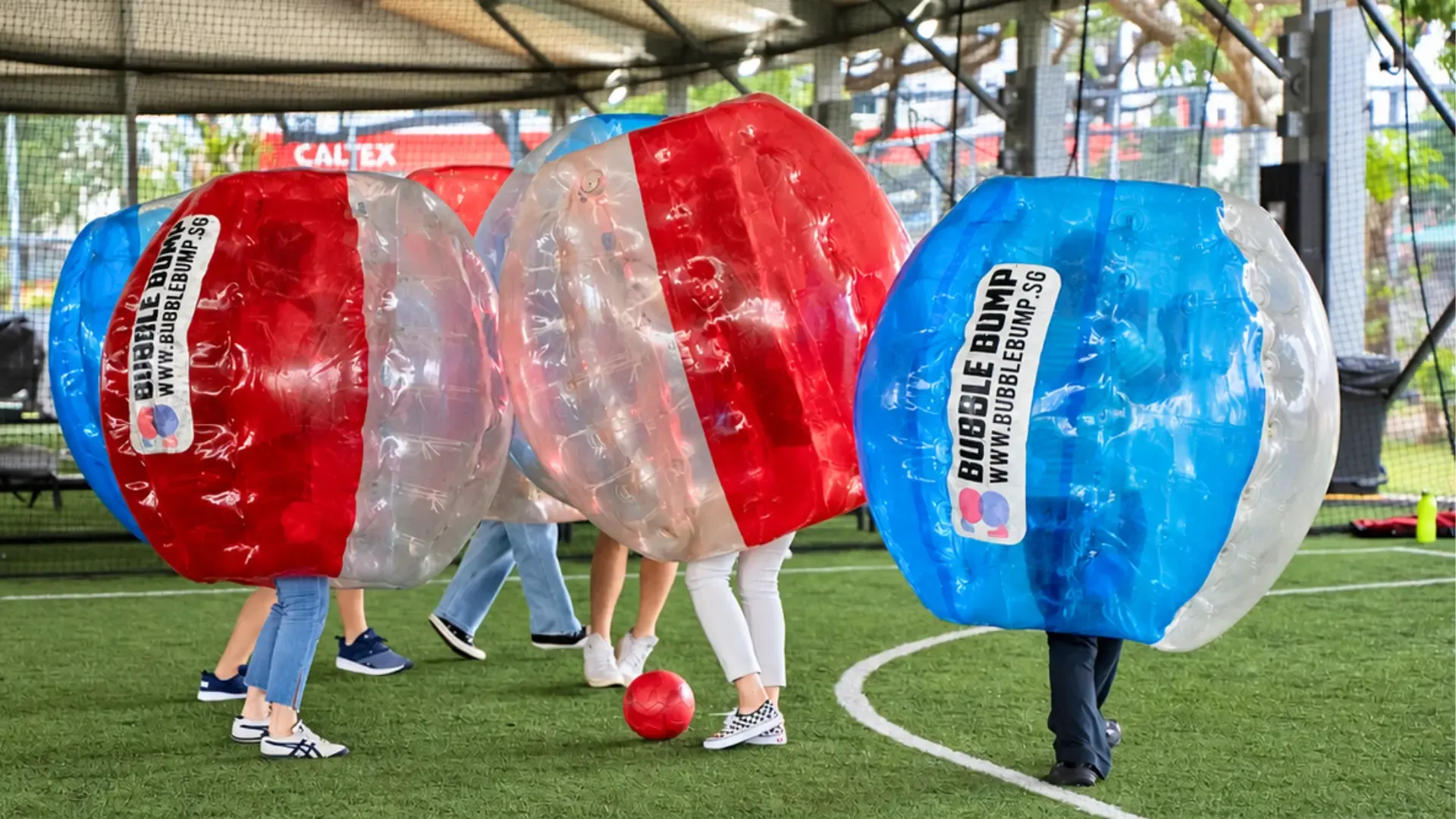 A row of players in red, blue and clear bubble suits on the turf