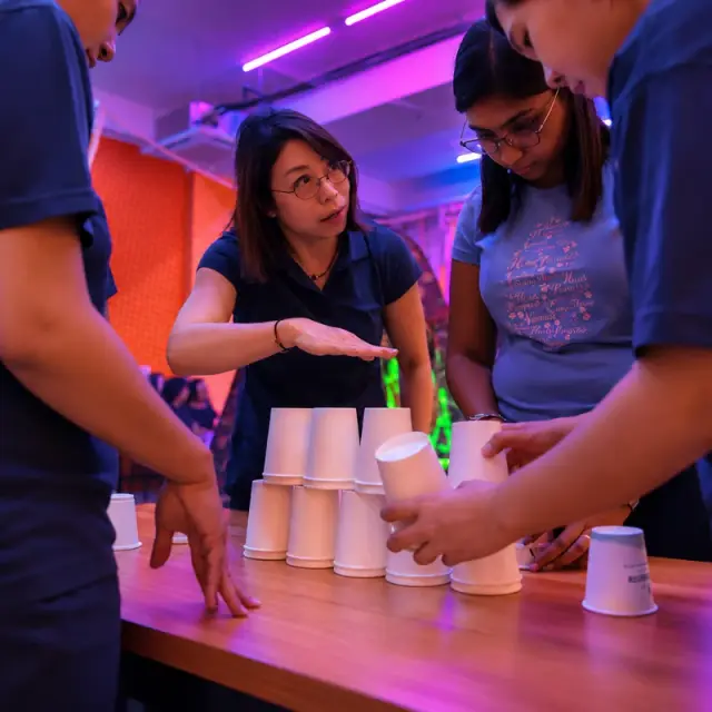 Teammates stack paper cups on a table in the studio