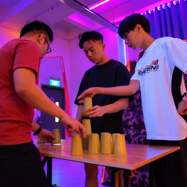 Three players stack cups on a table
