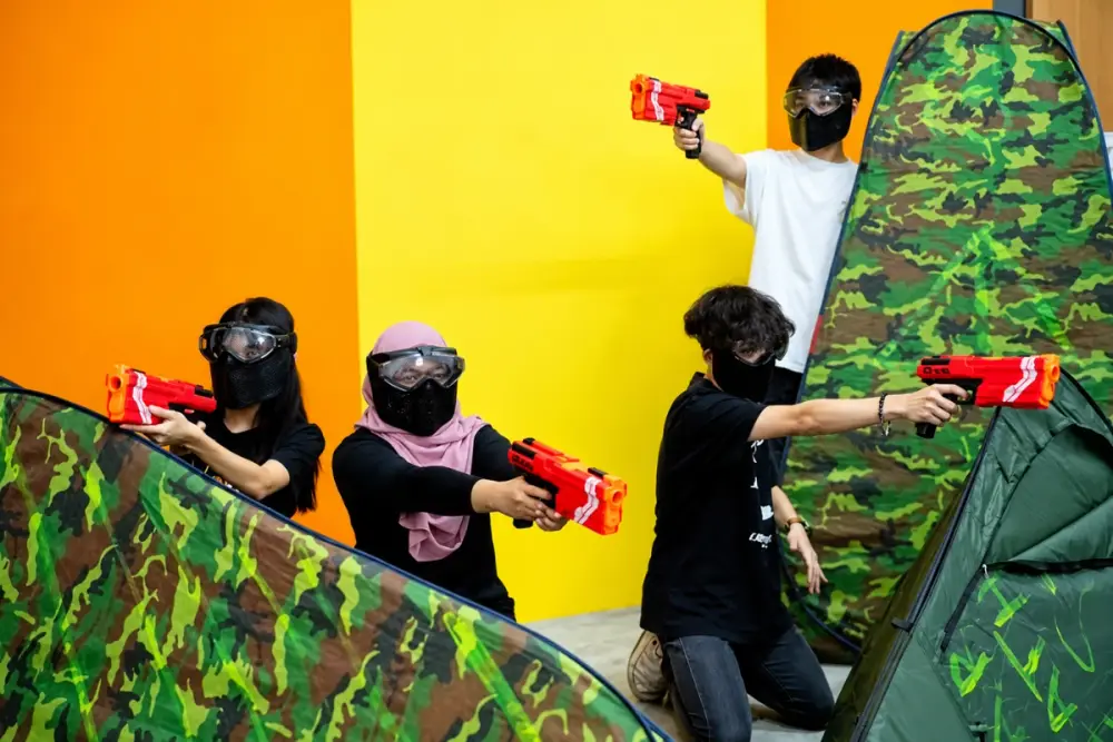 Four players in masks aim their blasters over the bunkers