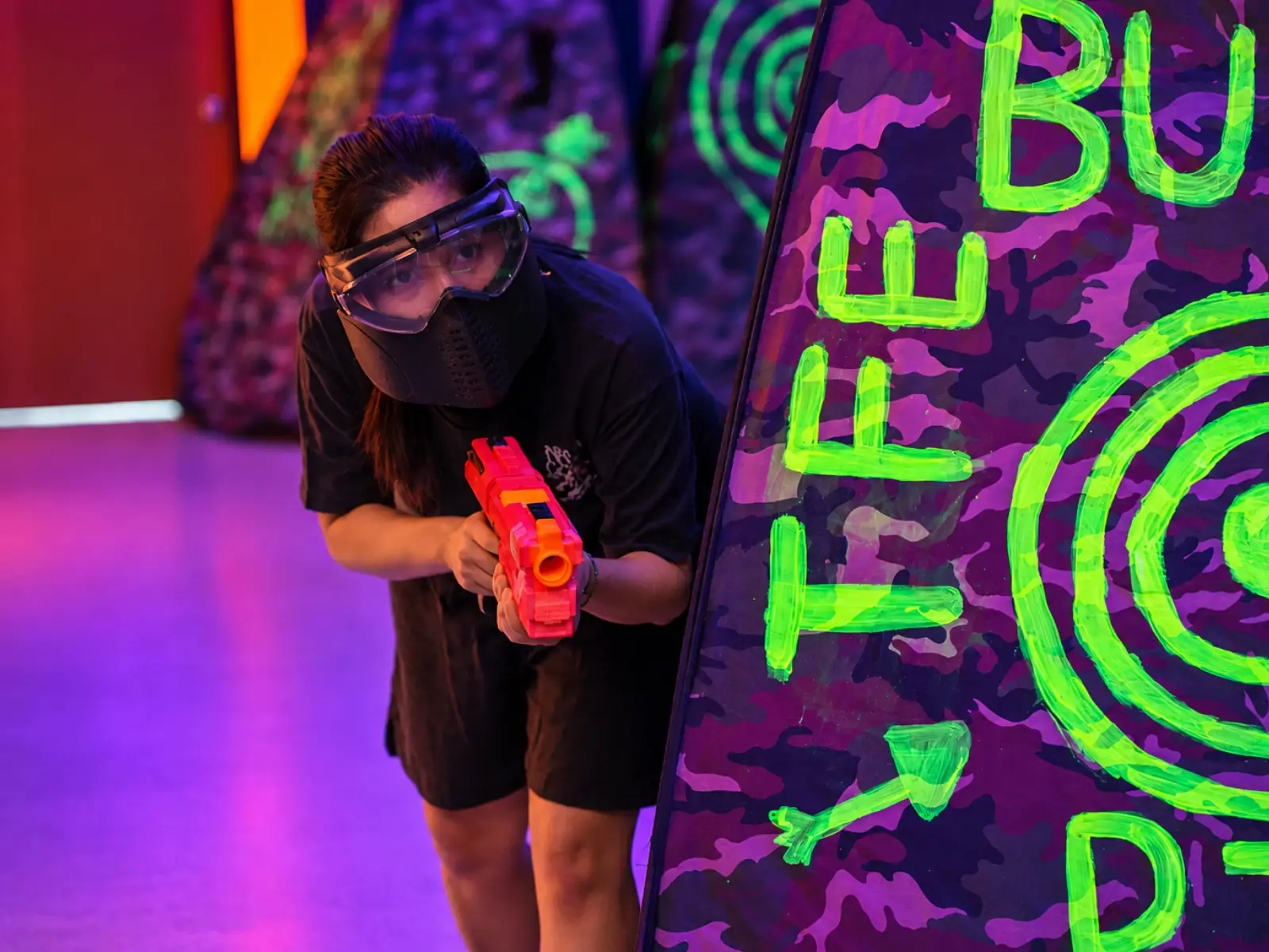 A player in a mask leans out from behind a bunker, blaster ready