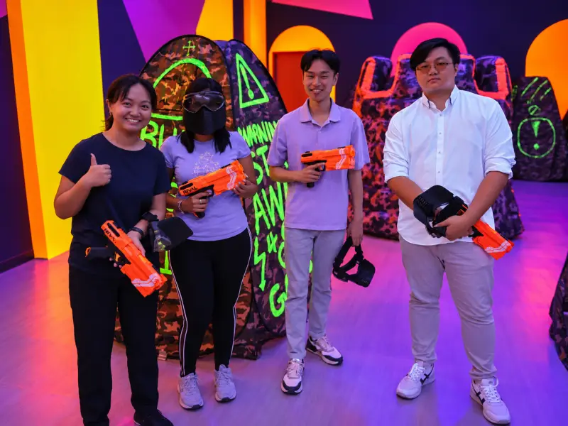 Four friends pose with their blasters, one giving a thumbs-up