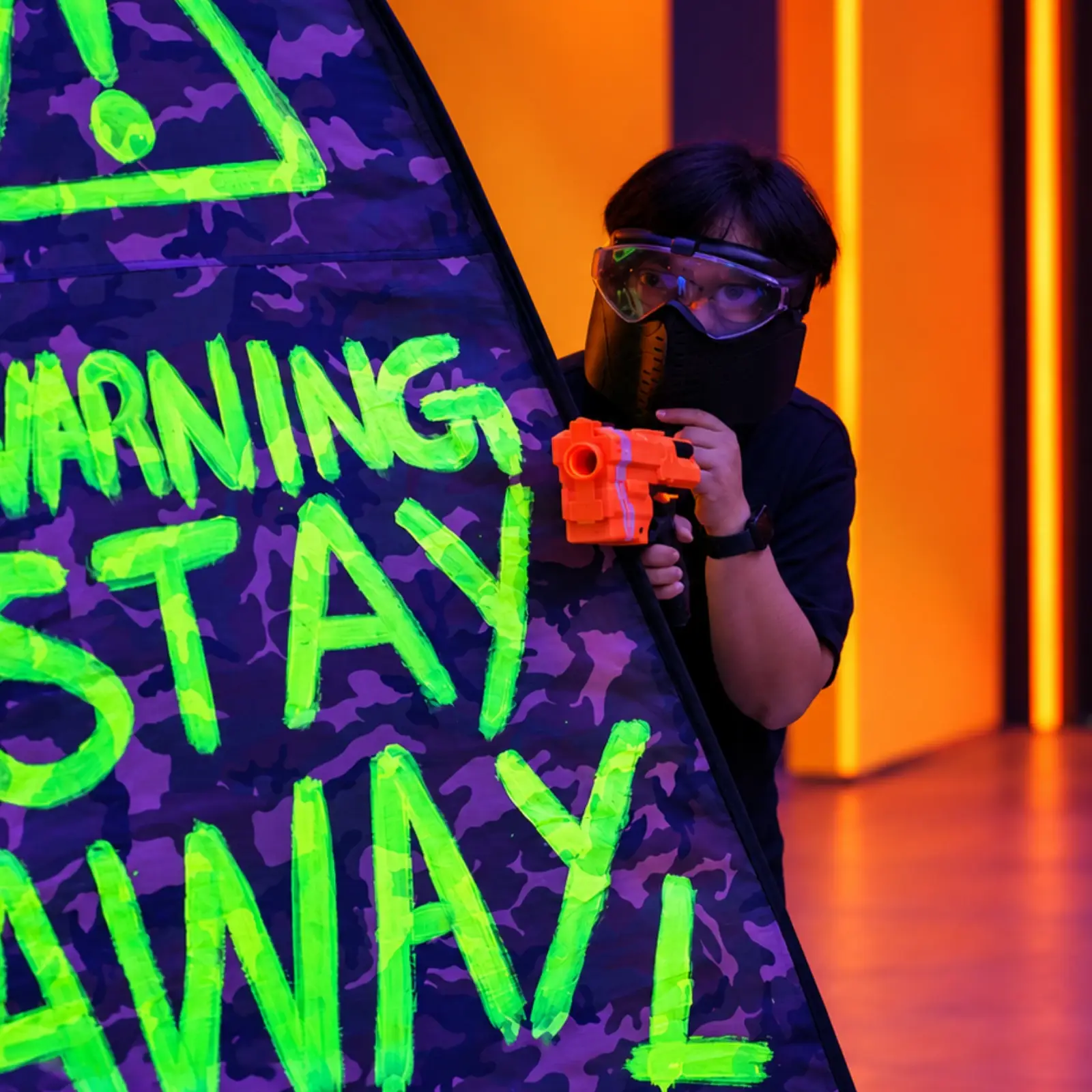 A player keeps watch from behind a bunker painted with a warning sign