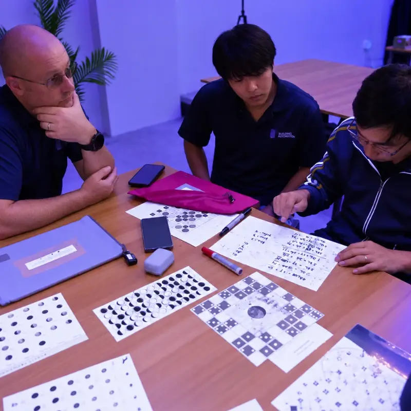 Three teammates study sheets of symbols