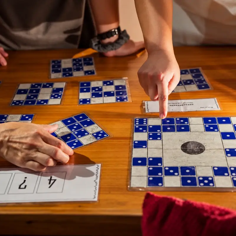 Hands point at blue-and-white tile puzzles on the table