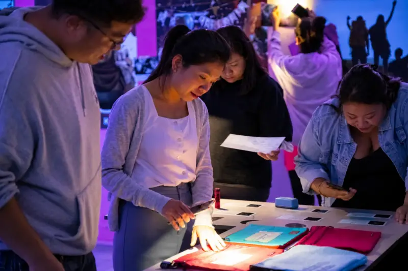 A team works at a lit table while others play behind them