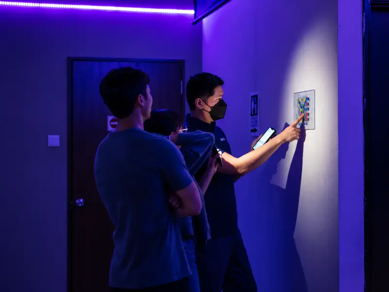 Players study a clue on the wall of a blue-lit corridor