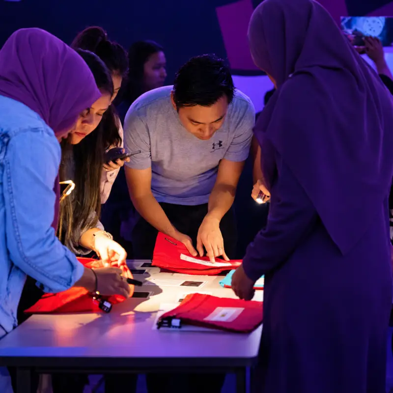 A group searches through red folders by torchlight