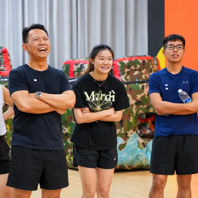 Three teammates laugh as they watch a round