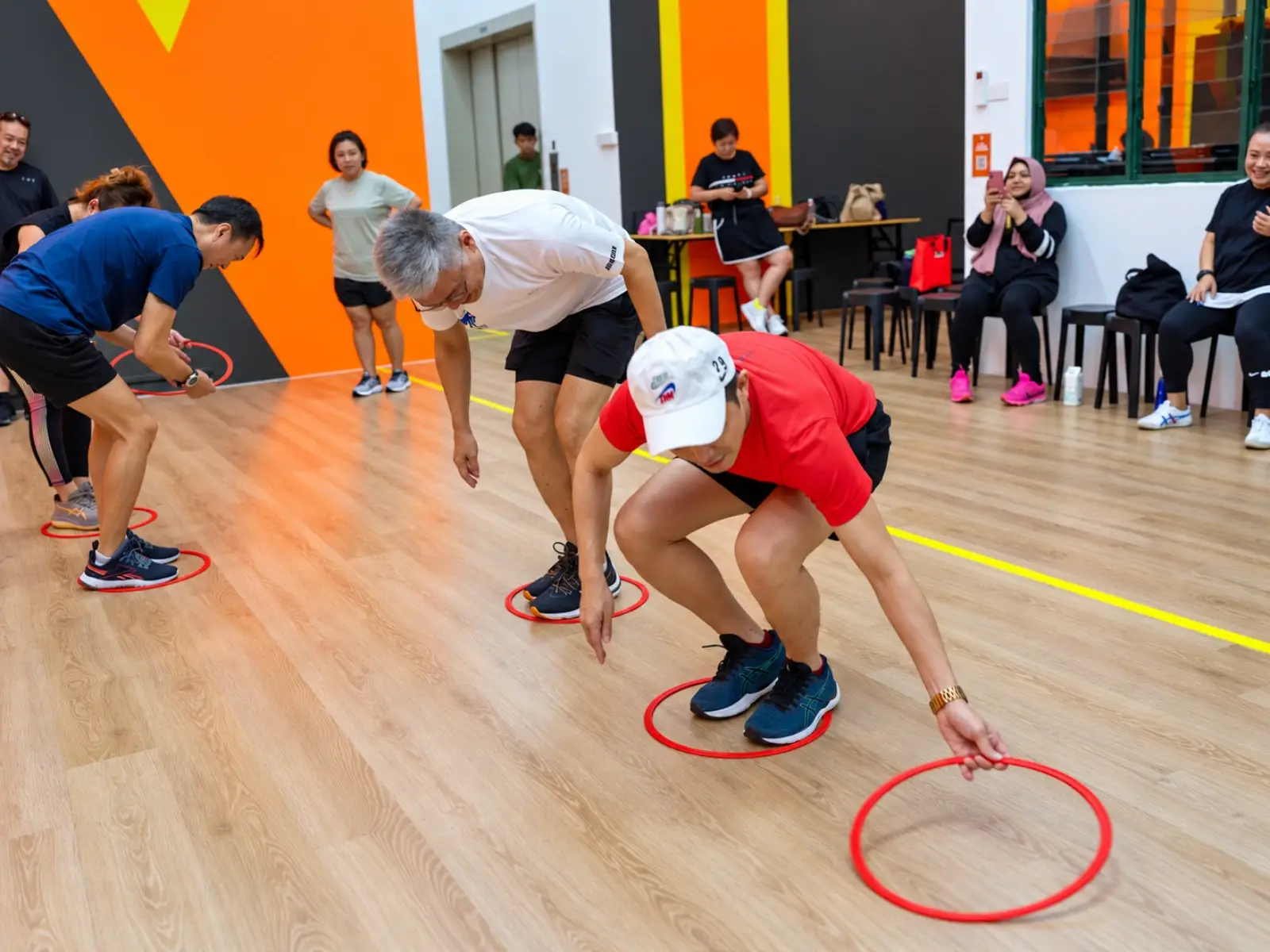Players reach for the next hoop on the floor while standing inside their own