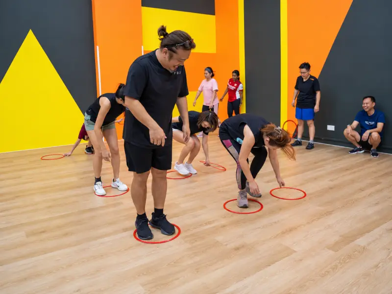 Players bend to the hoops at their feet while their teammates watch