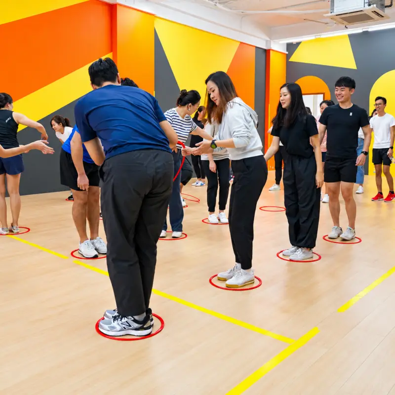 A team stands in a line of floor rings, hands joined, as a hoop travels down the line