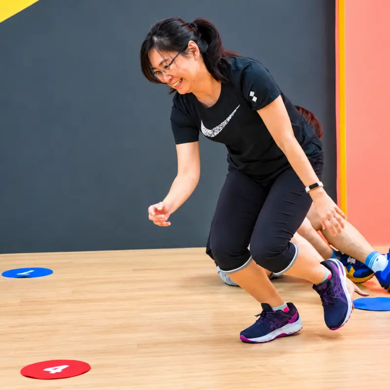 A player lunges across the floor between numbered discs, smiling