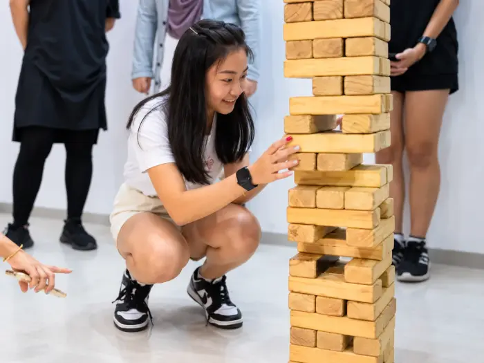 A player crouches beside a tall giant Jenga tower