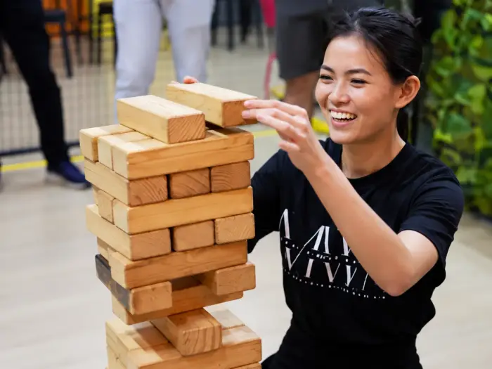 A player carefully pulls a block from a giant Jenga tower