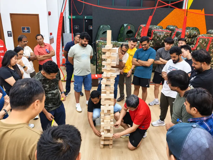 A crowd watches two players pull blocks from a towering giant Jenga