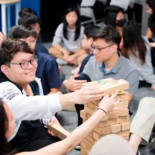 Hands passing a giant Jenga block between players