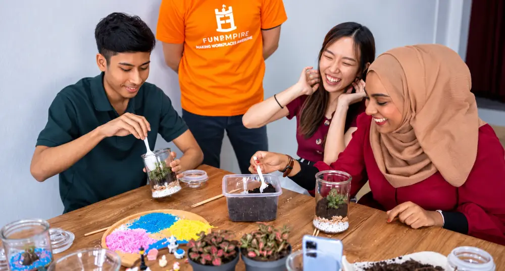 Participants laugh as they build their terrariums, with a FunEmpire facilitator on hand