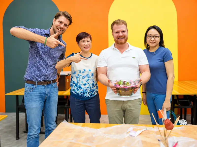 Four colleagues show the shared terrarium they built together