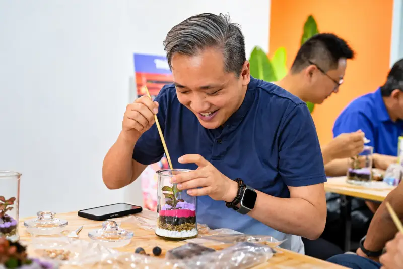 A participant smiles as he arranges the layers of his terrarium