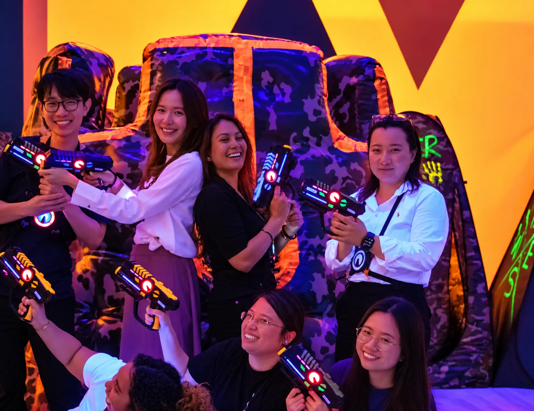 A group posing with laser blasters in the neon arena