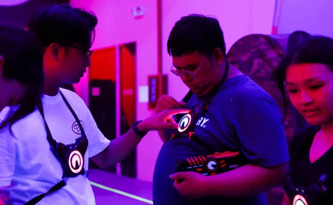 corporate team checking equipment and discussing before a game of laser tag in singapore
