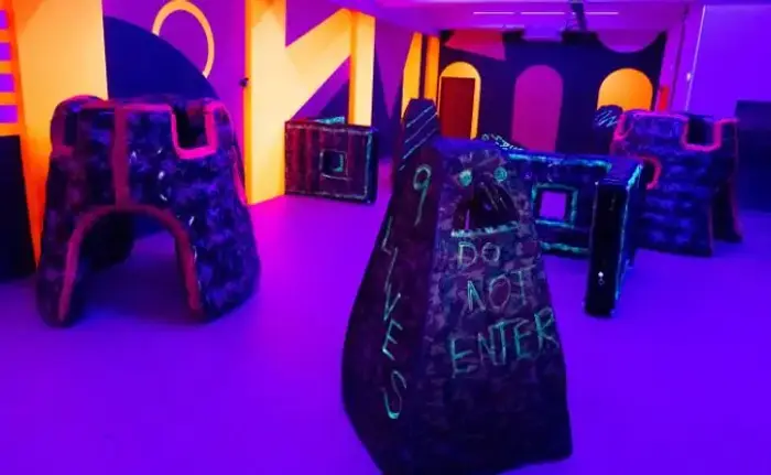 Neon-lit indoor laser tag studio with bunkers