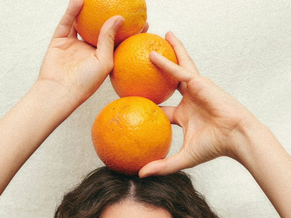 Hands playfully balancing fresh tangerines