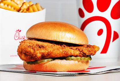 Chick-fil-A Chicken Sandwich with Waffle Fries and a drink in the background