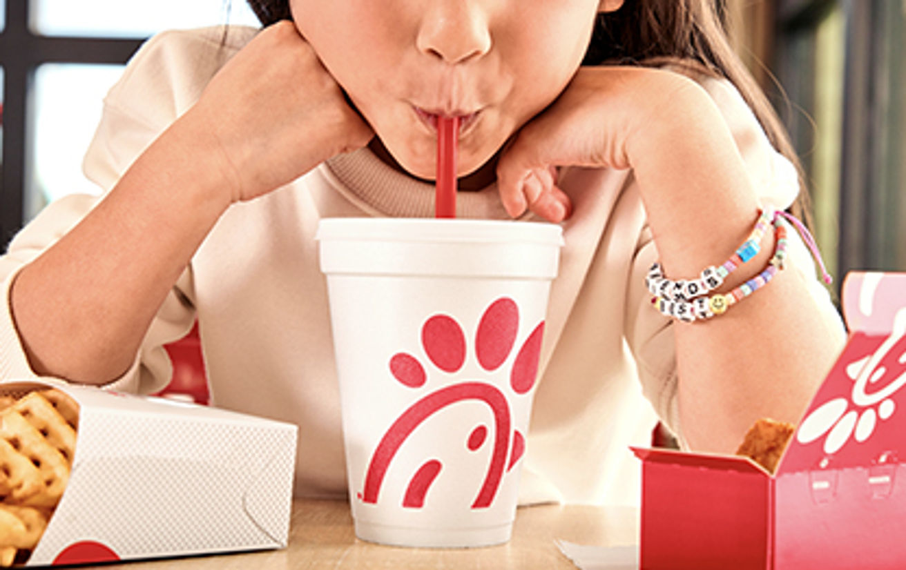 A girl sipping a beverage inside a Chick-fil-A Restaurant