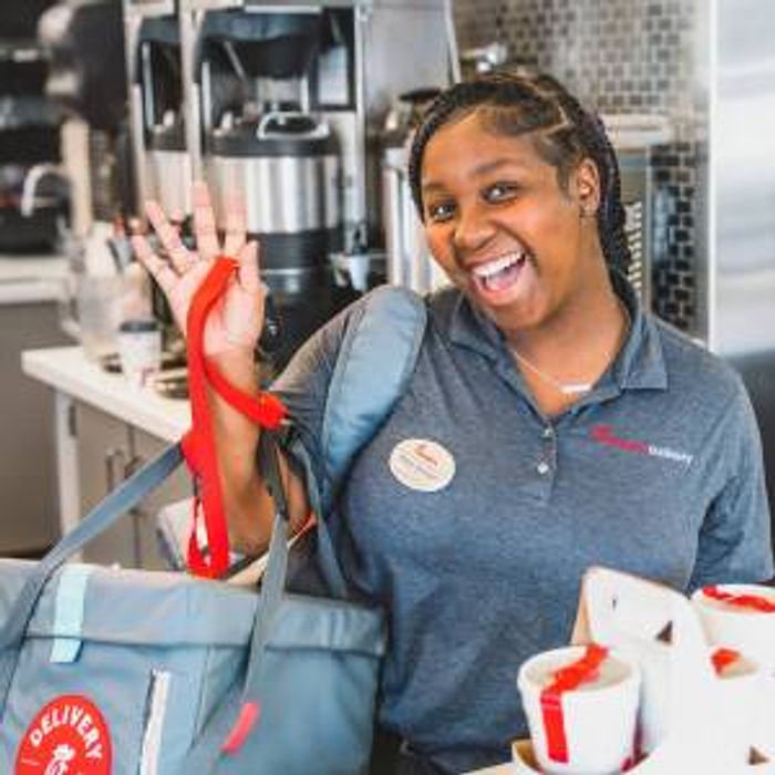 A Chick-fil-A Team Member smiling while holding delivery bags